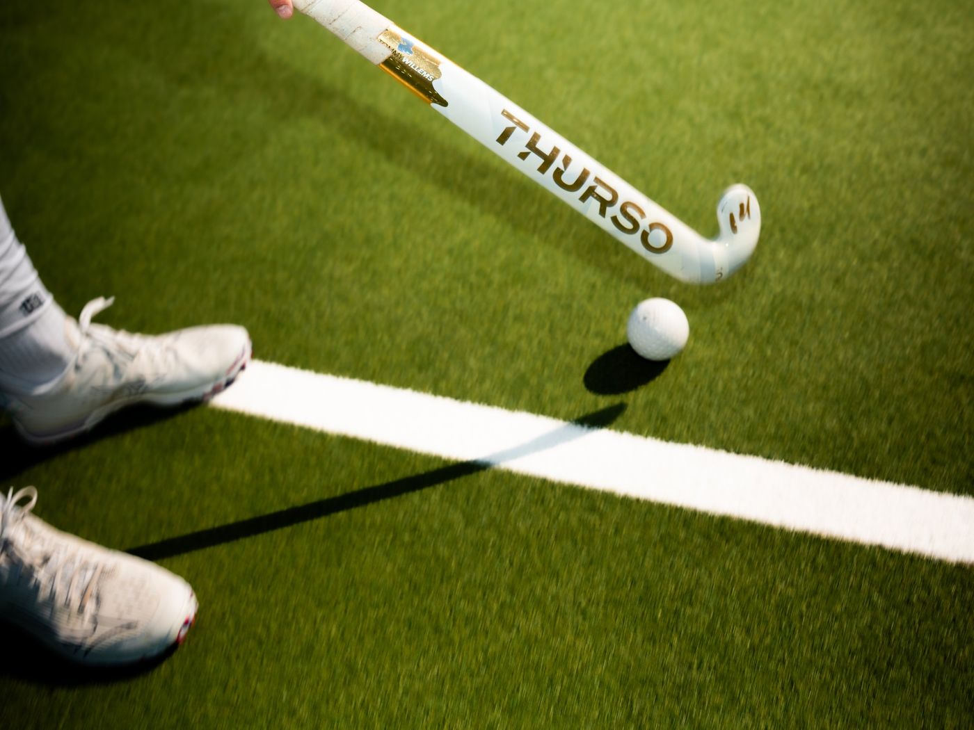 Stick de hockey et balle sur un terrain synthétique, photographie Néogif